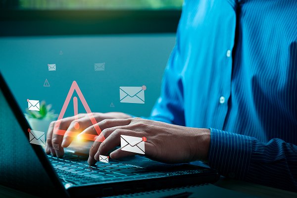 Person typing on a laptop with email icons and alert symbols, representing email marketing services offered by Always Top of Mind.